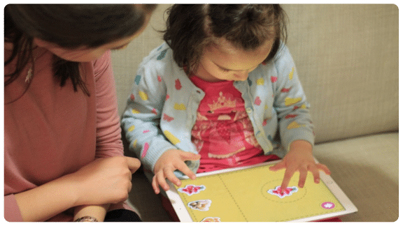 Kid playing with Otsimo with an adult by her side